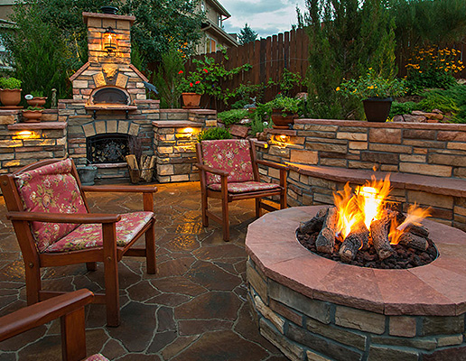 Outdoor kitchen and fireplaces in a backyard setting. 