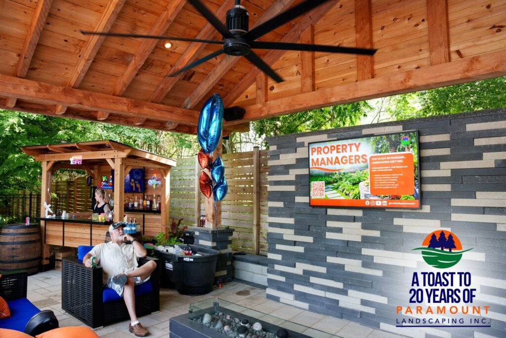 Guests gathered in the firepit lounge under a Douglas fir pergola beside one of the bars in Paramount Landscaping’s Discovery Lounge.
