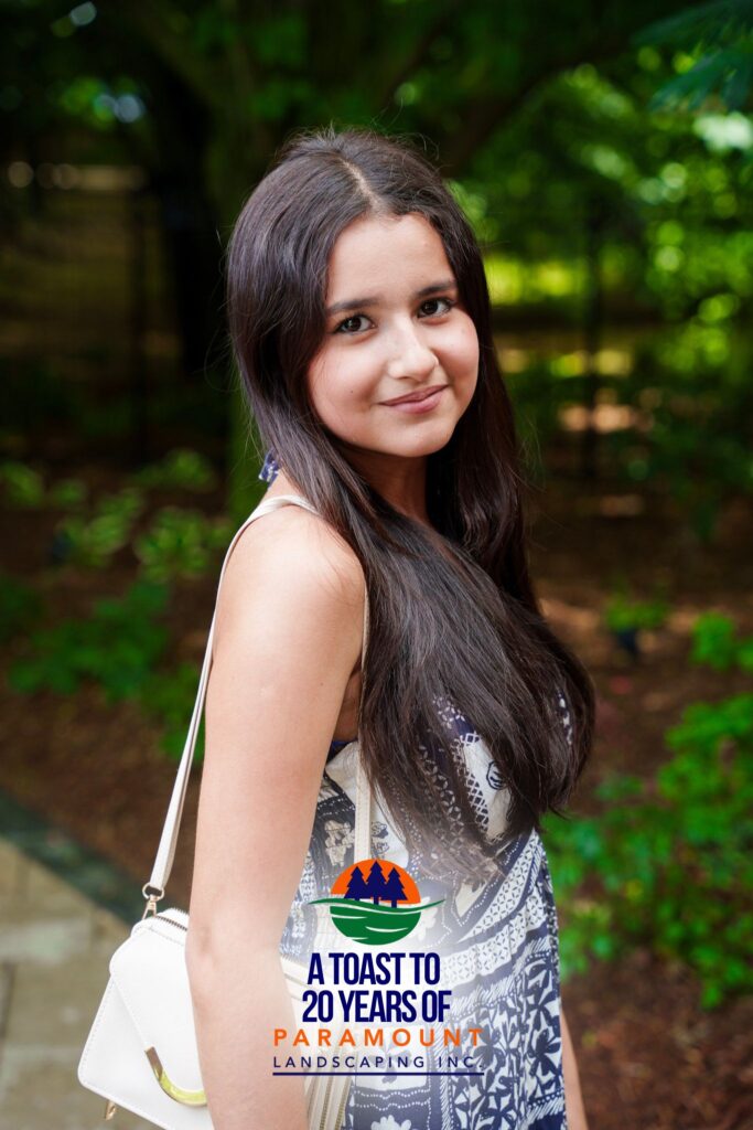 Woman in a floral dress smiling while helping run the 360° camera at Paramount Landscaping’s 20th anniversary event.