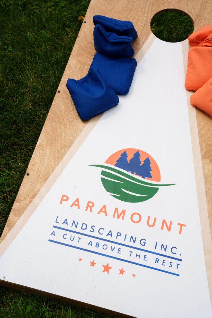 Close-up of a custom Paramount Landscaping cornhole board with a beanbag in play, made by local Milton-based maker Barn Door Studio.