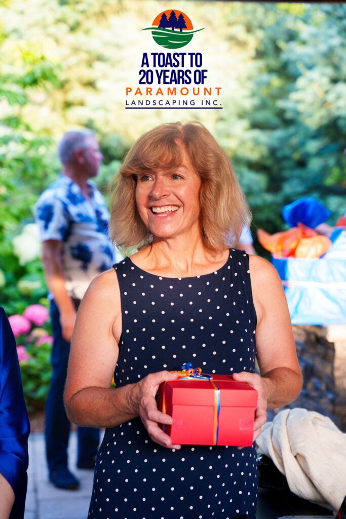 Diana Ward of Paramount Landscaping smiles while holding a giveaway prize during the company’s 20th anniversary celebration.