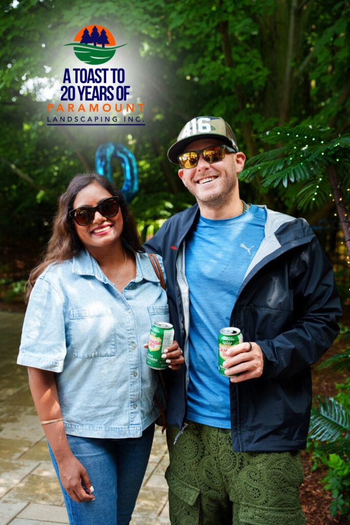 A couple posing together at Paramount Landscaping's 20th Anniversary event, standing in front of a branded backdrop.